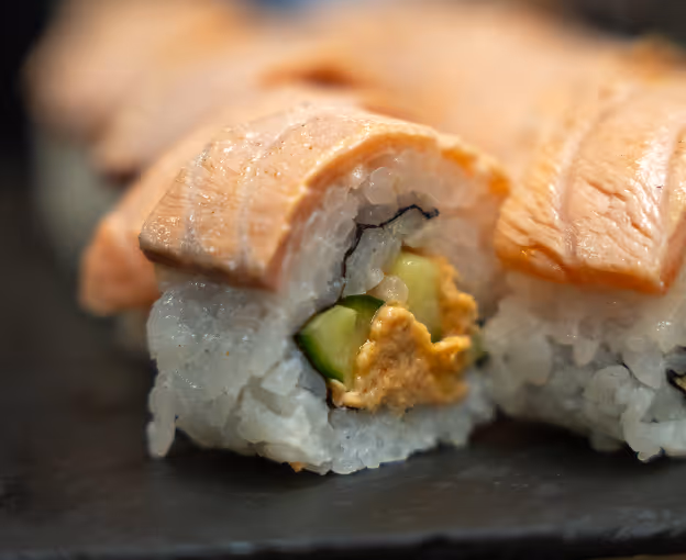 Sushi roll with salmon, cucumber, and sauce filling.